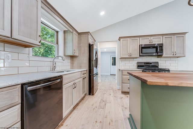 kitchen featuring appliances with stainless steel finishes, lofted ceiling, butcher block counters, sink, and light wood-type flooring