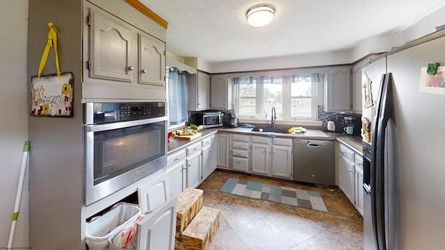 kitchen with light tile patterned flooring, backsplash, appliances with stainless steel finishes, and gray cabinets