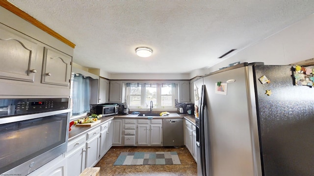 kitchen with a textured ceiling, gray cabinets, stainless steel appliances, tile patterned floors, and sink