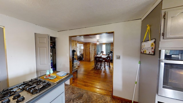 kitchen featuring white cabinetry, a textured ceiling, hardwood / wood-style flooring, and stainless steel appliances