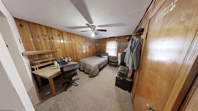 bedroom with wood walls, light carpet, ceiling fan, and a textured ceiling