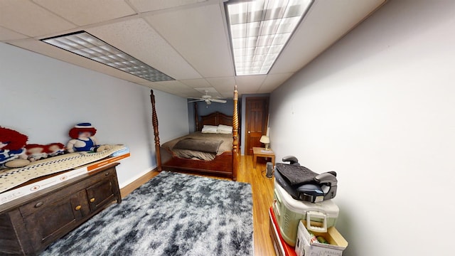 bedroom with a drop ceiling and wood-type flooring