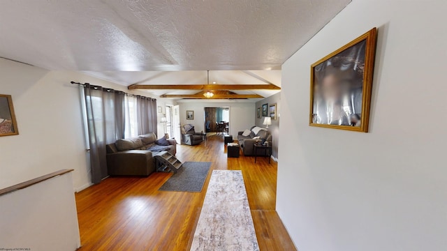 living room featuring a textured ceiling, hardwood / wood-style floors, and beam ceiling