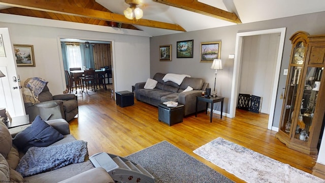 living room featuring light hardwood / wood-style floors, ceiling fan, and vaulted ceiling with beams