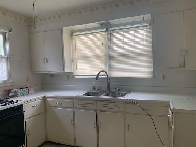 kitchen with range with gas cooktop, white cabinets, and sink