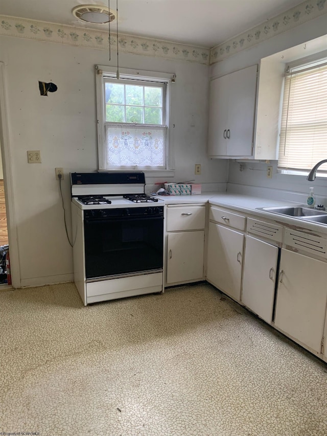 kitchen with white cabinetry, gas range, and sink