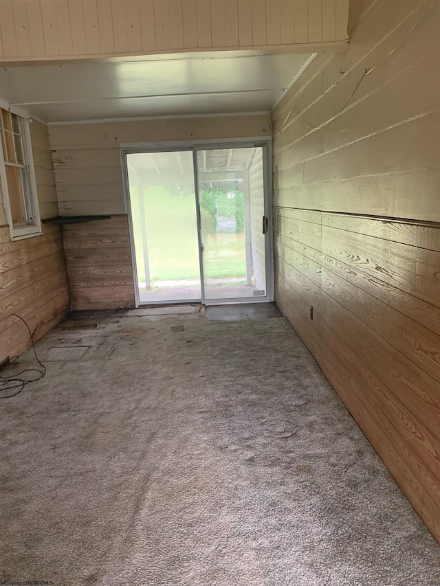 carpeted empty room featuring wooden walls