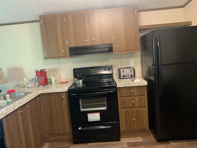 kitchen featuring black appliances, light hardwood / wood-style floors, and sink