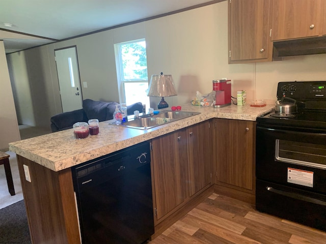 kitchen with sink, black appliances, kitchen peninsula, and light wood-type flooring