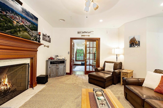 living room featuring ceiling fan, light colored carpet, french doors, and a premium fireplace