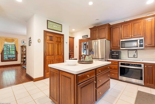 kitchen with light tile patterned floors, appliances with stainless steel finishes, and a kitchen island