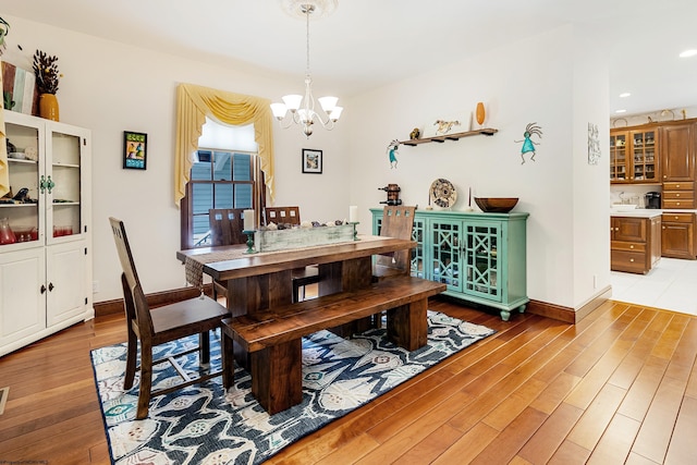 dining space with hardwood / wood-style floors and a notable chandelier