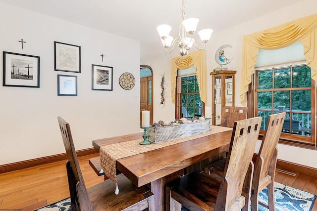 dining area featuring wood-type flooring and a notable chandelier