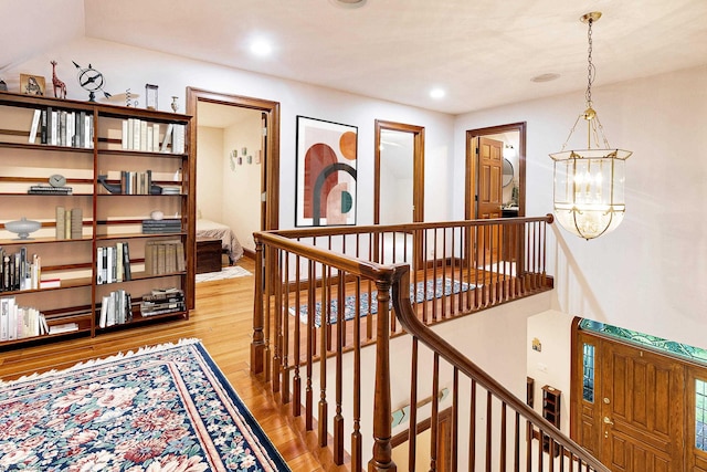 hallway with light hardwood / wood-style floors and a chandelier