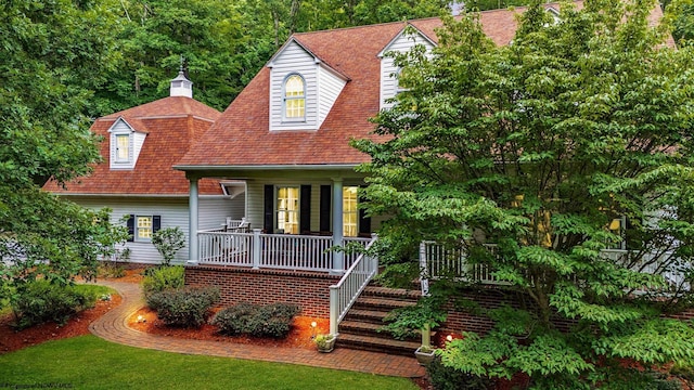 cape cod home featuring covered porch