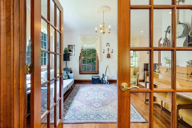 entryway with hardwood / wood-style floors, french doors, and a notable chandelier