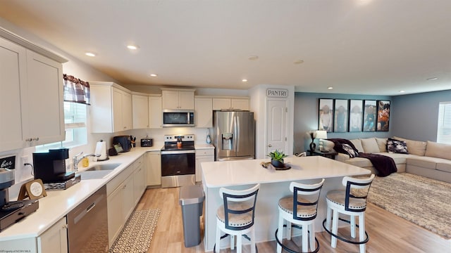 kitchen featuring sink, a breakfast bar area, a center island, light hardwood / wood-style flooring, and appliances with stainless steel finishes