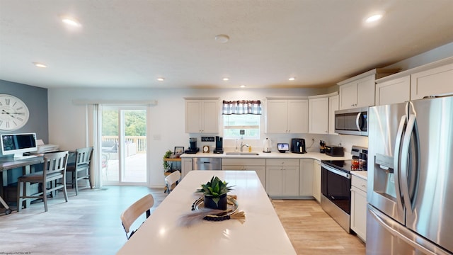 kitchen with stainless steel appliances, white cabinetry, plenty of natural light, and sink