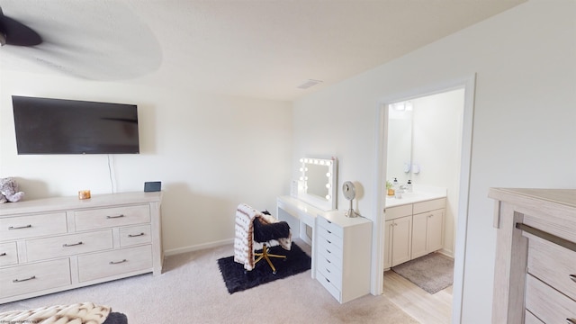 bedroom with ensuite bathroom and light colored carpet