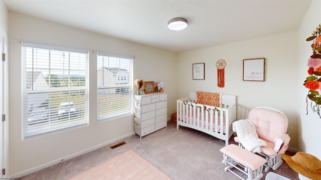 carpeted bedroom featuring multiple windows and a crib