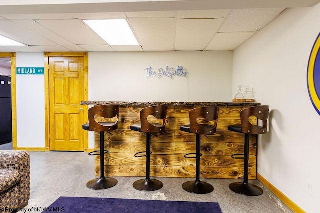 bar with black fridge and a paneled ceiling