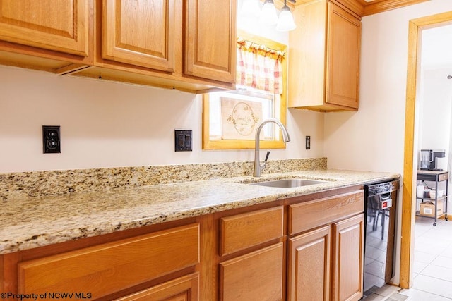 kitchen with light tile patterned flooring, black dishwasher, sink, and light stone countertops