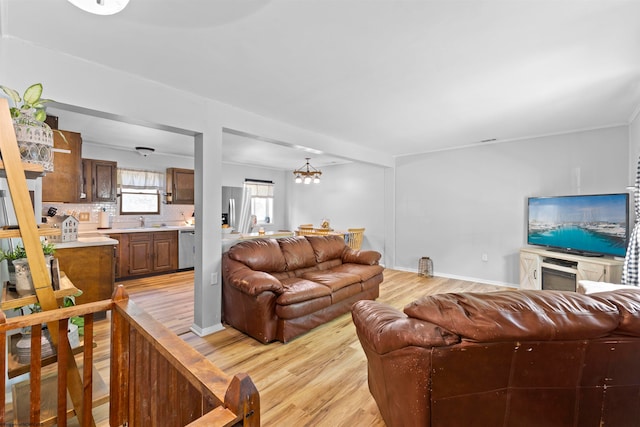 living room featuring an inviting chandelier, sink, and light hardwood / wood-style floors