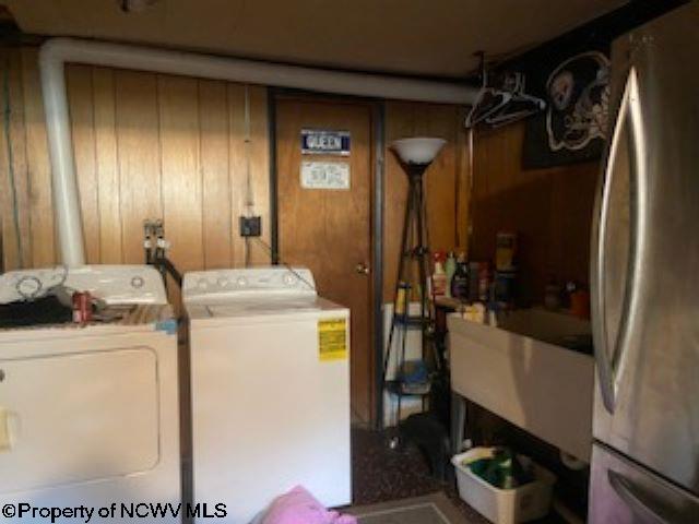 laundry area with sink, washing machine and clothes dryer, and wooden walls