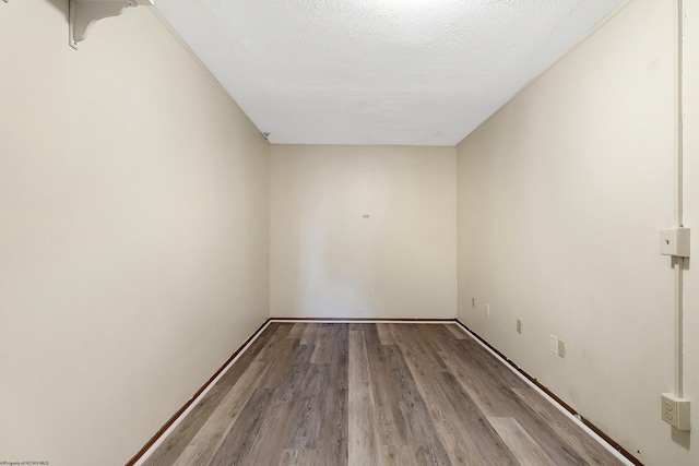 unfurnished room featuring a textured ceiling and light wood-type flooring