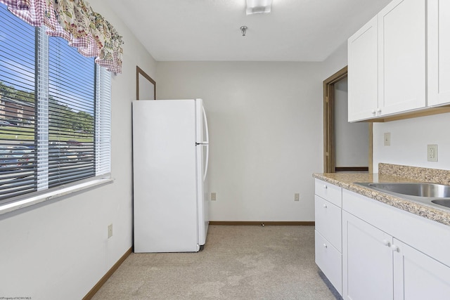 kitchen featuring white refrigerator, white cabinetry, and sink