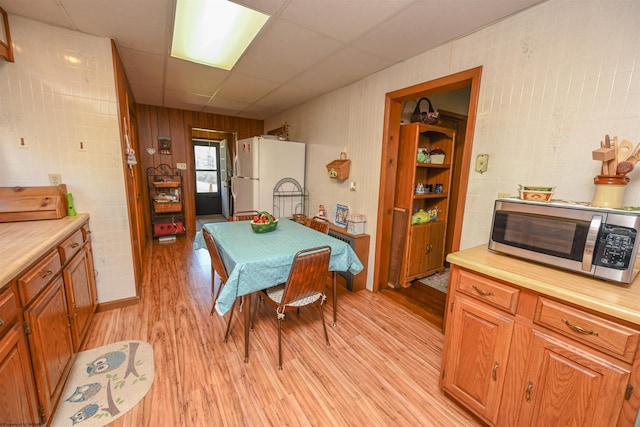 dining area with light hardwood / wood-style floors and a paneled ceiling