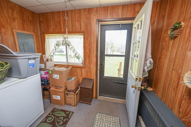 doorway featuring light colored carpet, wooden walls, and a paneled ceiling