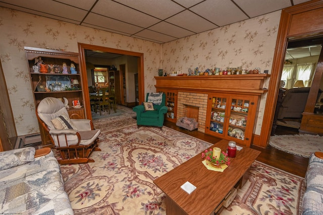 interior space featuring a fireplace, a paneled ceiling, hardwood / wood-style flooring, and baseboard heating