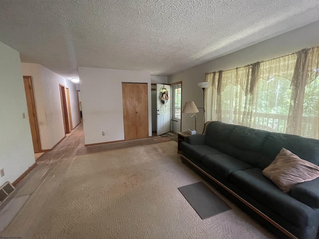 living area featuring light colored carpet, a textured ceiling, and baseboards