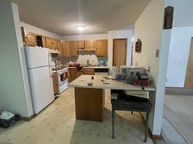 kitchen featuring white appliances, light countertops, a textured ceiling, under cabinet range hood, and a sink