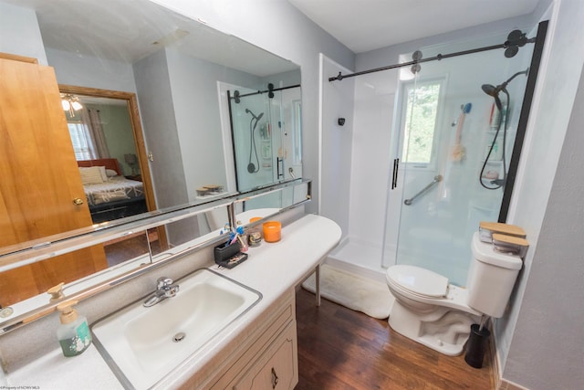 bathroom with a shower with door, vanity, hardwood / wood-style flooring, and toilet