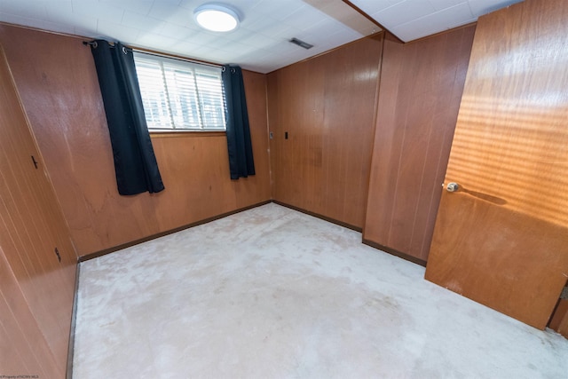 carpeted spare room with wooden walls