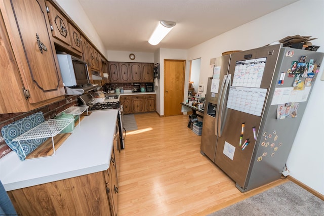 kitchen featuring stainless steel appliances, light hardwood / wood-style floors, and backsplash