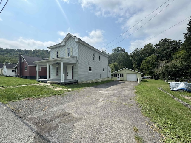 view of front of property featuring a garage, an outdoor structure, a porch, and a front yard