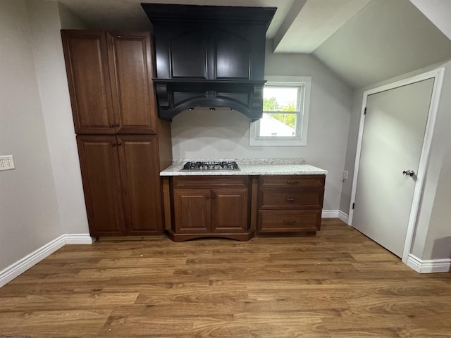 kitchen featuring dark wood-type flooring, lofted ceiling, stainless steel gas stovetop, and dark brown cabinetry