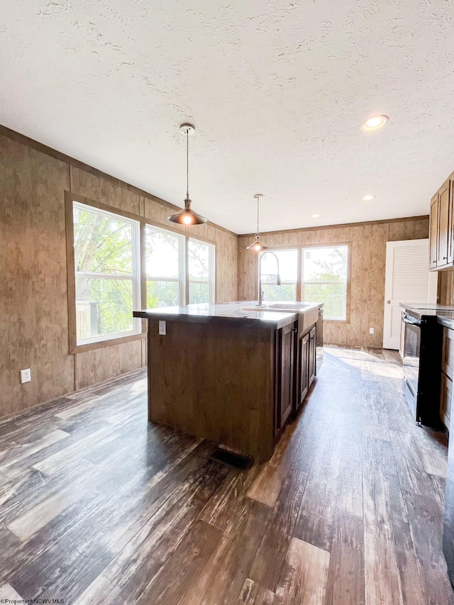 kitchen with sink, a kitchen island, decorative light fixtures, electric range, and dark hardwood / wood-style flooring