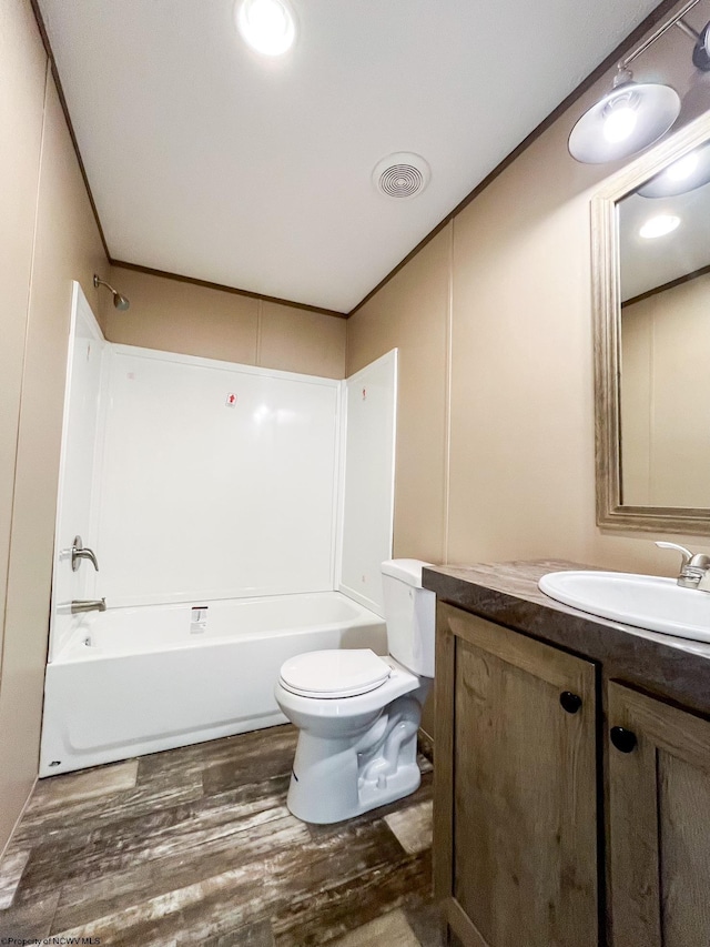 full bathroom with hardwood / wood-style flooring, toilet, bathtub / shower combination, ornamental molding, and vanity