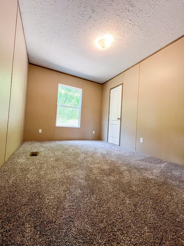 carpeted spare room with a textured ceiling