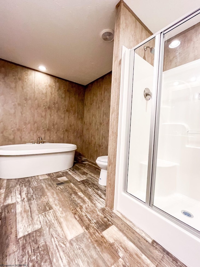 bathroom with plus walk in shower, toilet, and hardwood / wood-style floors