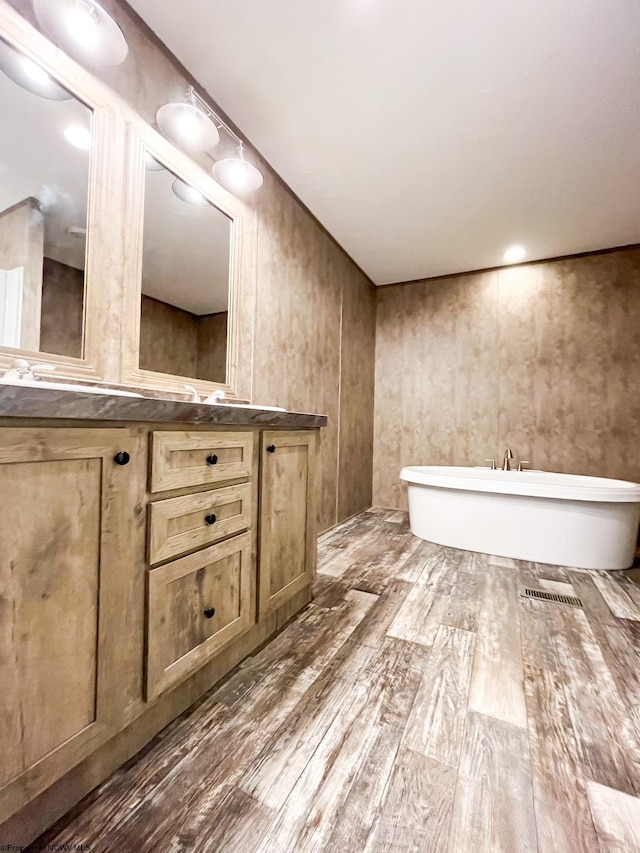 bathroom featuring wood-type flooring, vanity, and a bathing tub