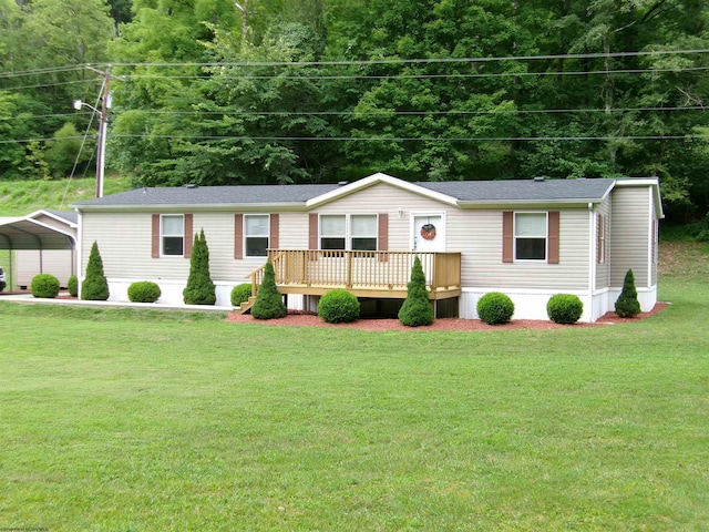 manufactured / mobile home featuring a wooden deck, a carport, and a front yard