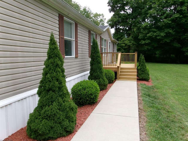 view of side of home with a deck and a lawn