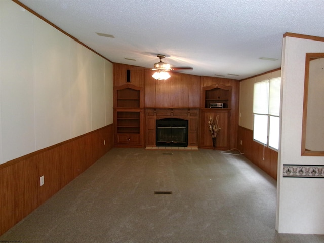 unfurnished living room with light carpet, a textured ceiling, and wood walls