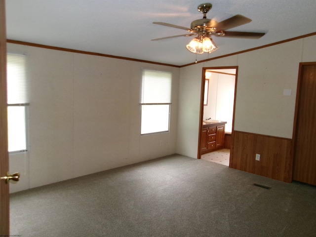 unfurnished room with crown molding, light carpet, ceiling fan, and wooden walls