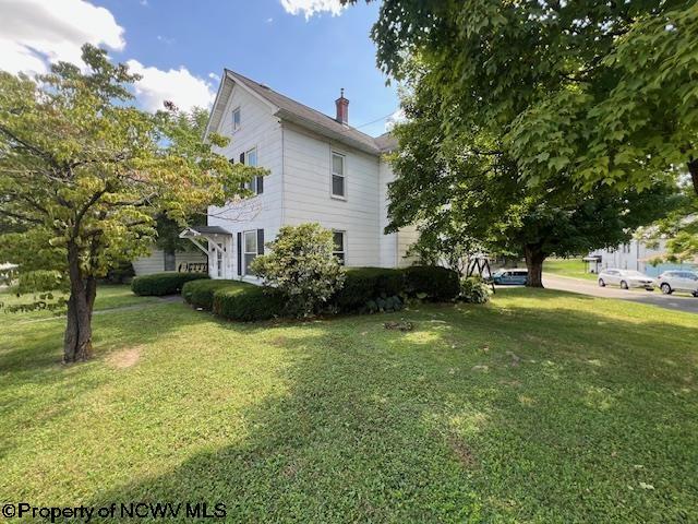 view of side of property with a lawn and a chimney